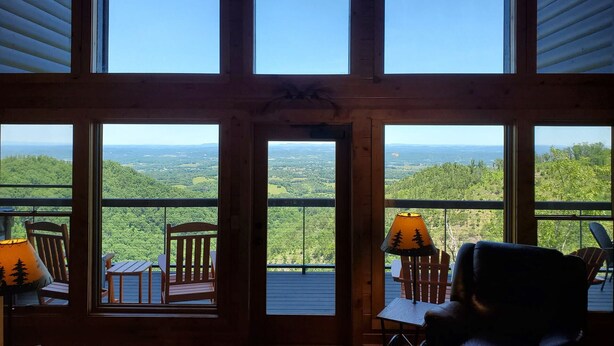 Habitación con amplios ventanales que dan a un paisaje boscoso.