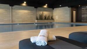 Ein moderner Innenpoolbereich mit großem Schwimmbecken, dunkler Decke und minimalistischer Einrichtung.