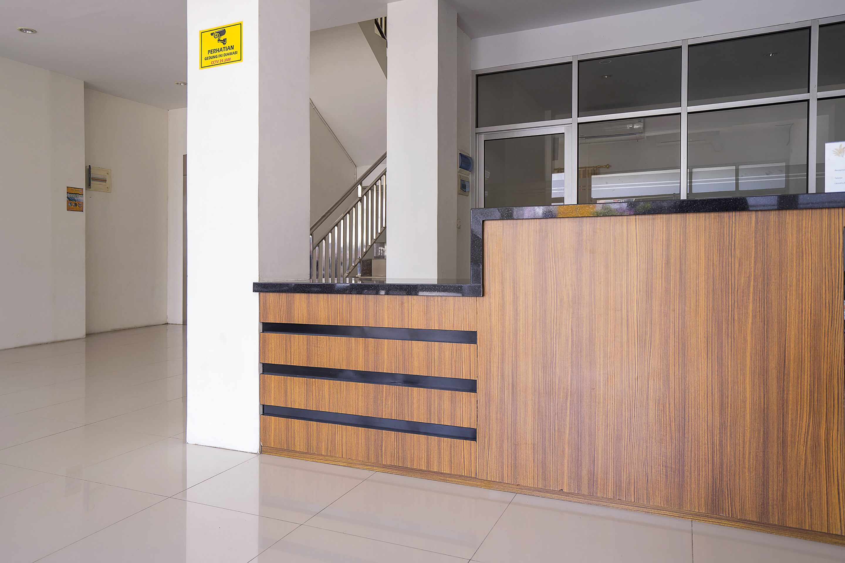 A reception desk with a wooden finish and a glass window above it.