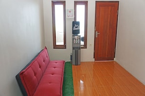A room with a red sofa, a water dispenser, a first aid box, and a wooden door. - OYO 2860 The Castury Homestay Syariah (Panimbang)