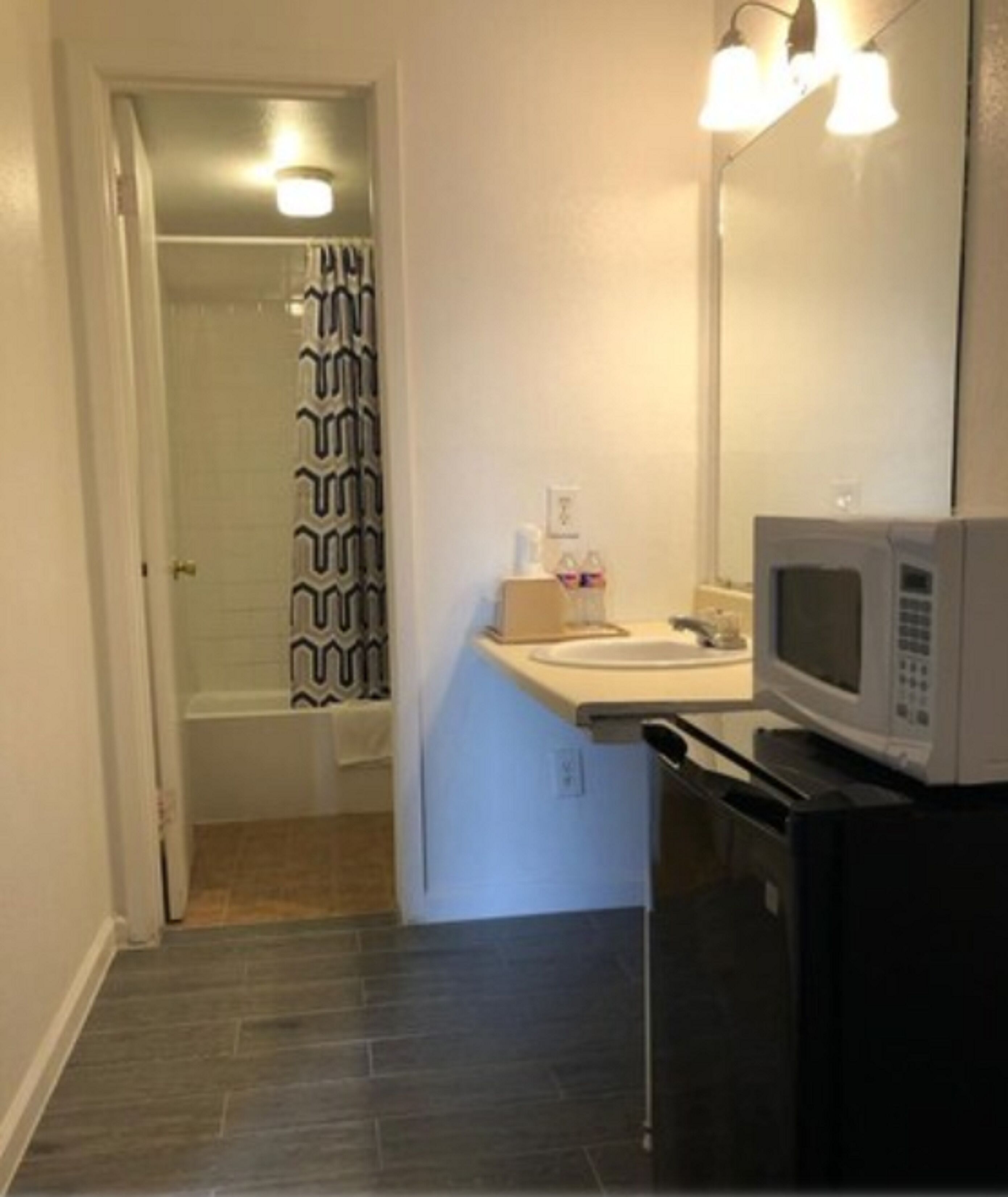 Casa de banho compacta com chuveiro, lavatório e micro-ondas.