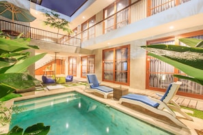 Ein Poolbereich mit Liegestühlen, einer Treppe und einem Balkon mit Blick.