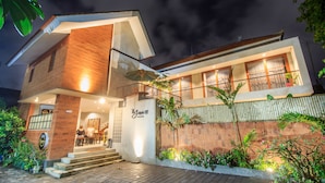 Una casa moderna de dos pisos con una entrada bien iluminada, una escalera visible y un balcón.