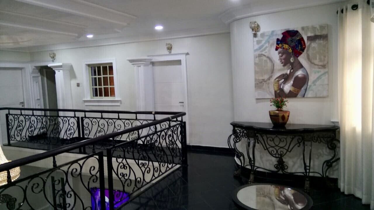 A hotel lobby with a staircase, a painting on the wall, and a potted plant on a console table.