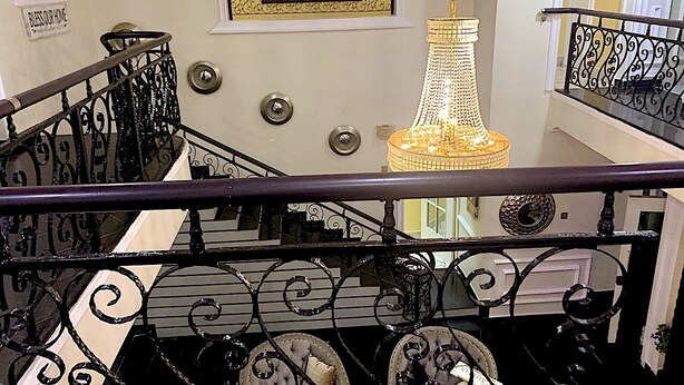 A grand staircase with ornate black railings and a chandelier. - Exquisite home. Perfect home away from home (Lagos Mainland)