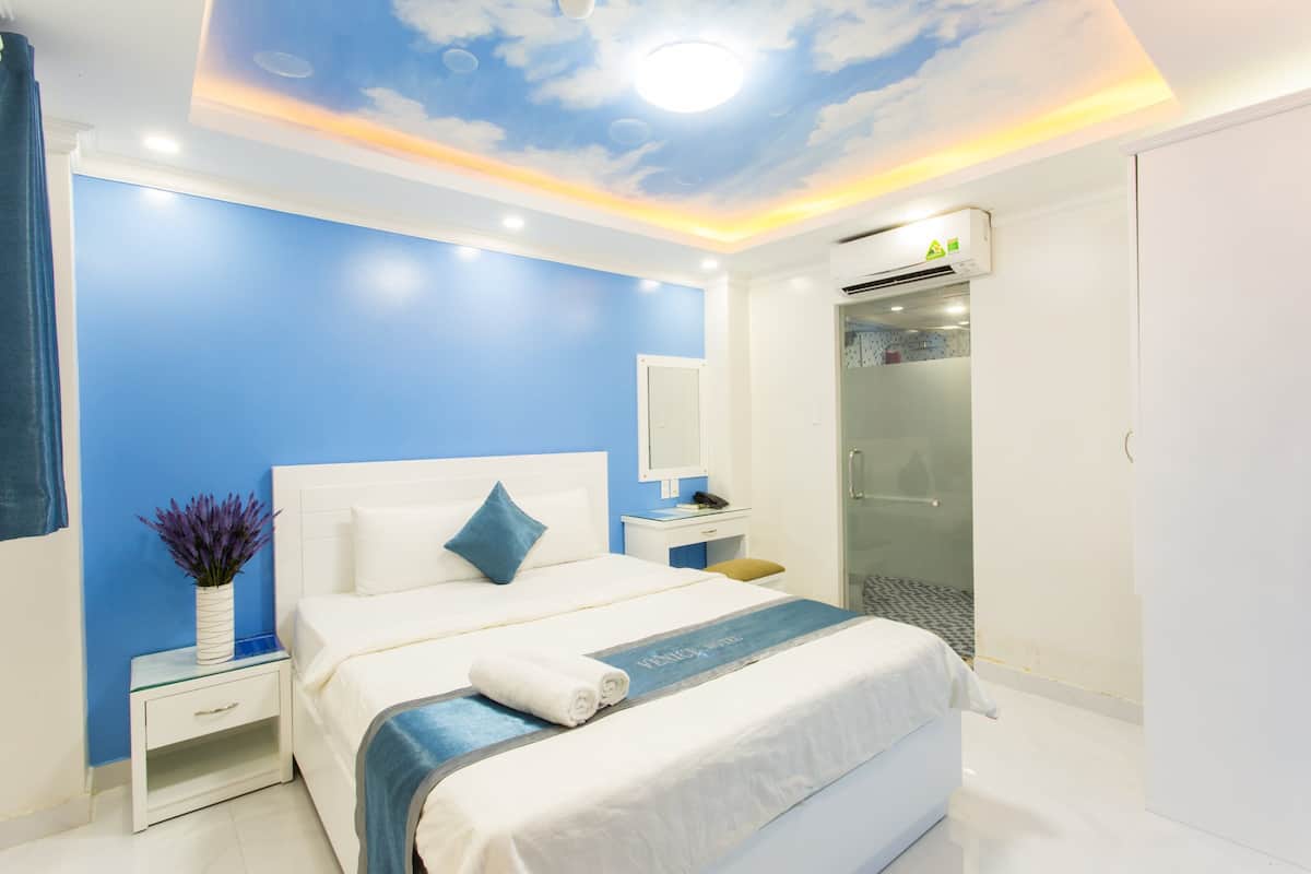 Habitación de hotel con cama, mesita de noche y zona de ducha.