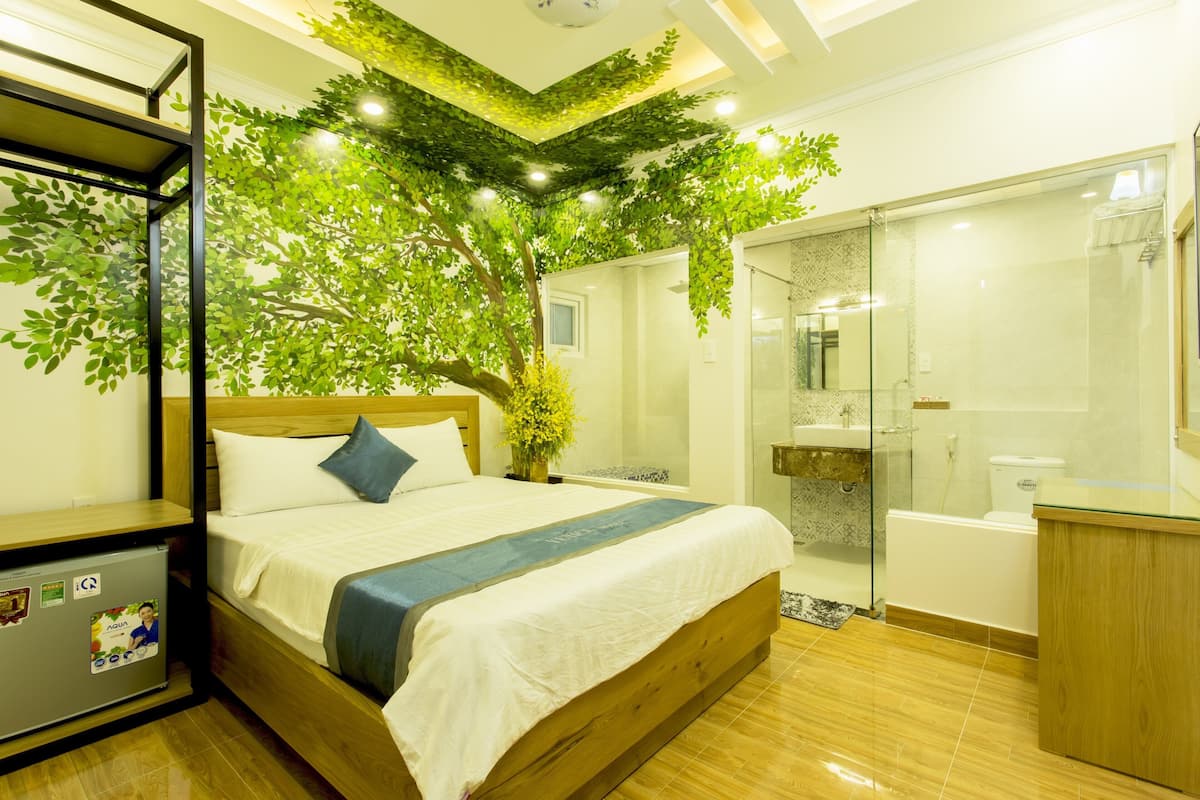 Una habitación de hotel moderna con una cama, un escritorio pequeño, ducha y baño.