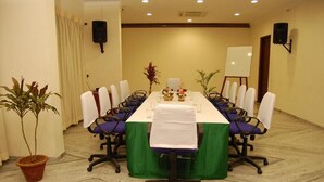 A conference room with a long table, chairs, a whiteboard, and speakers. - The Golden Park (Madurai)