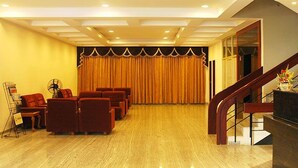 A hotel lobby with a reception desk, a staircase, and several seating areas. - The Golden Park (Madurai)