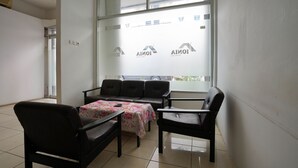A waiting area with a sofa, chairs, and a table with a floral tablecloth.