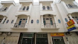 A multi-story building with balconies, a storefront with a sign, and a flag.