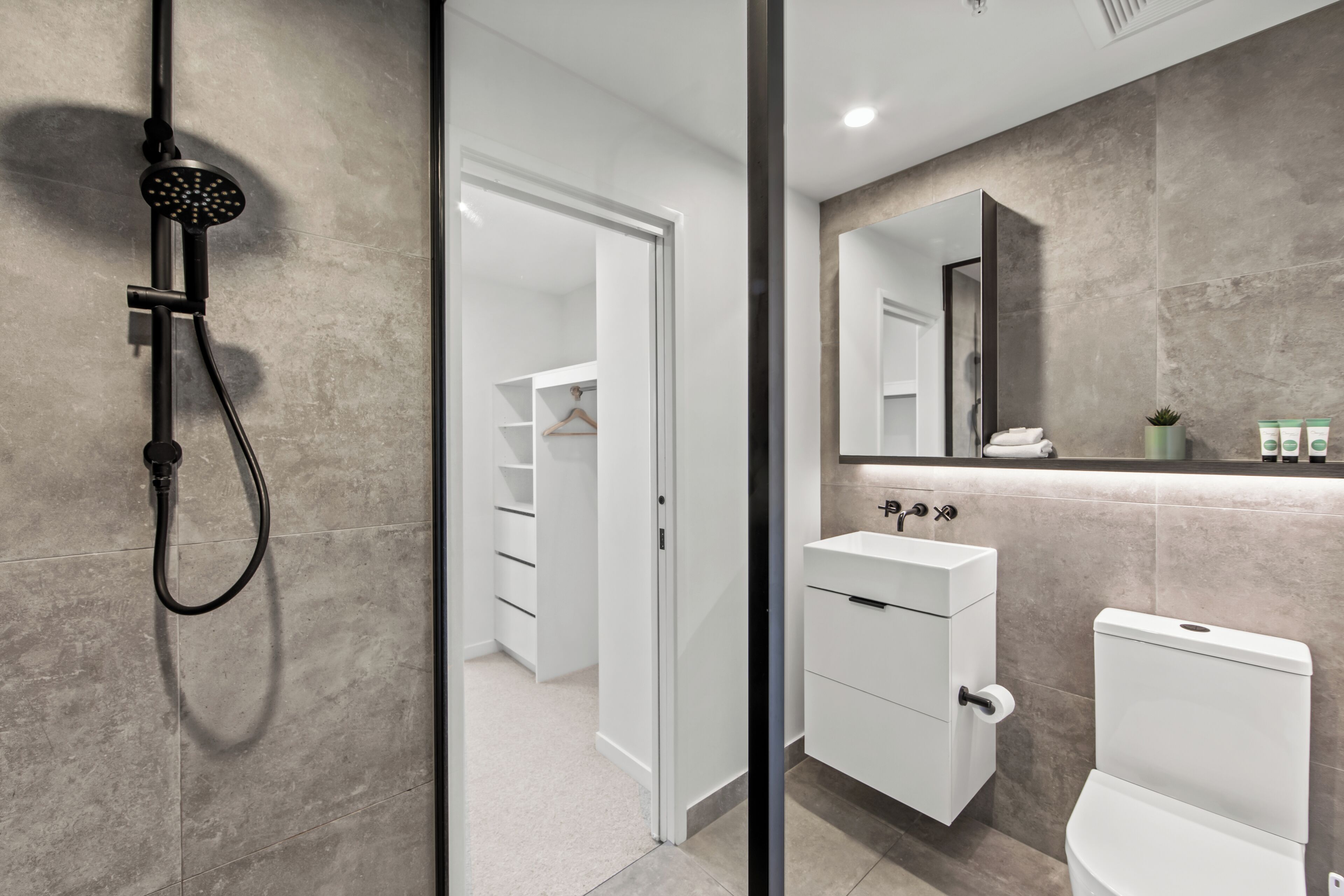 A modern bathroom with a shower, toilet, and sink.