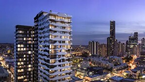 Un edificio alto con múltiples balcones, rodeado por un paisaje urbano al anochecer.