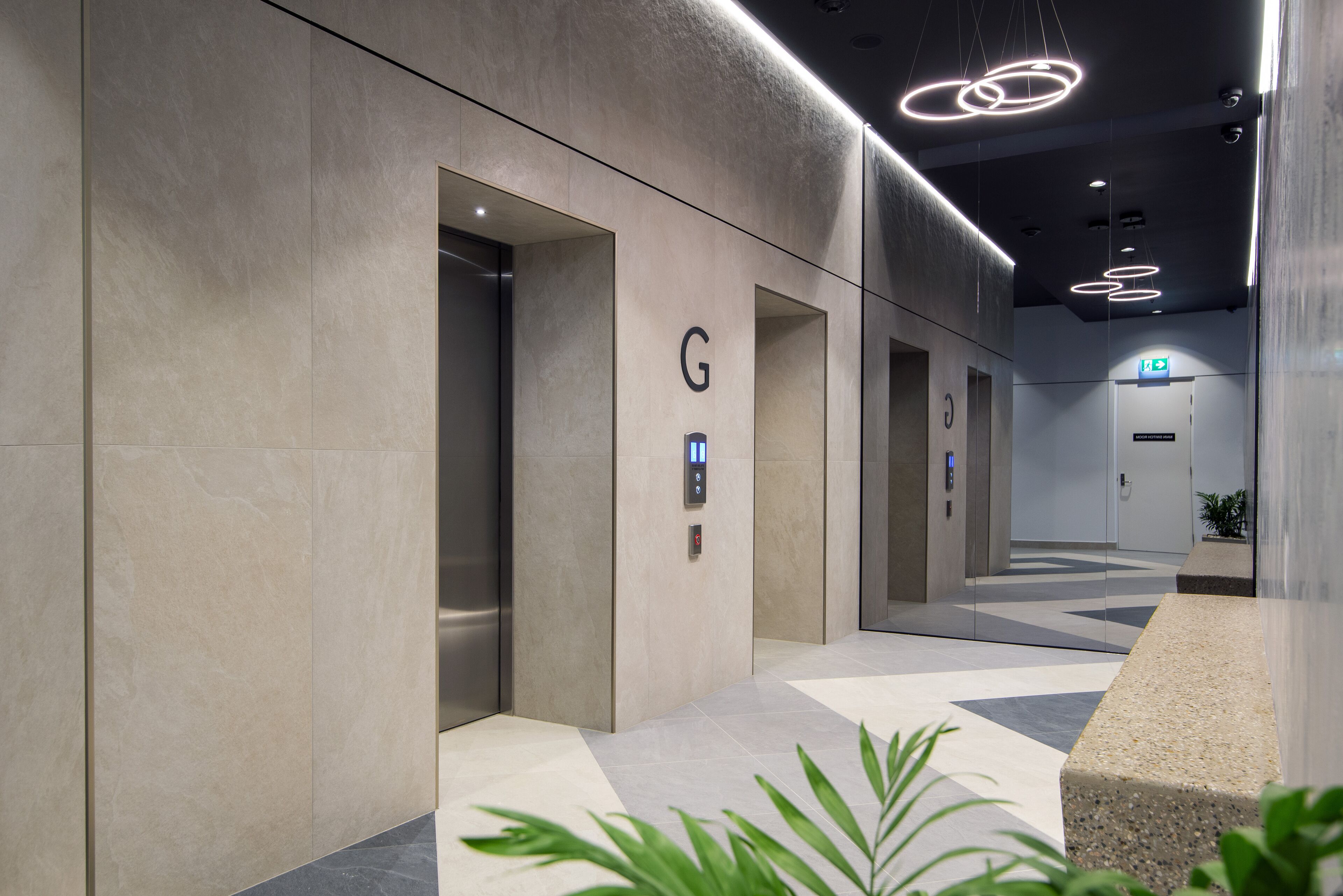 A modern hallway with elevators, a geometric patterned floor, and a minimalist design.