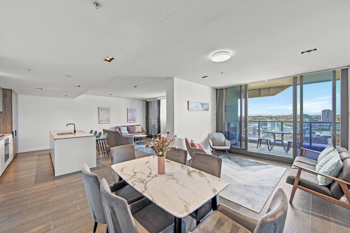 Een modern appartement met een eetgedeelte, keuken en een balkon met uitzicht over de stad.