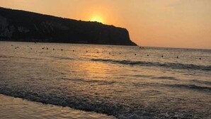 A beach with waves at sunset, a cliff in the background, and a clear sky. - Theodos Lodge Hotel By Hansa (Batroun)