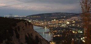 Uma vila costeira ao entardecer, com vista para o mar e colinas ao fundo.
