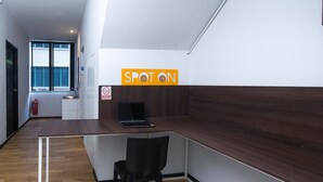 Un espacio de oficina moderno con un escritorio de madera, una silla negra y un ordenador portátil. Un cartel en la pared dice "SPOT ON".
