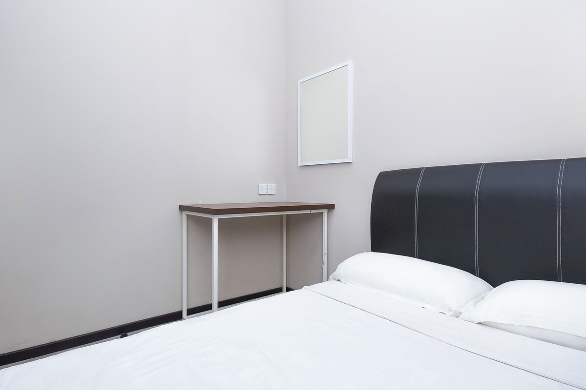 A hotel room with a bed, a desk, and a wall-mounted mirror.