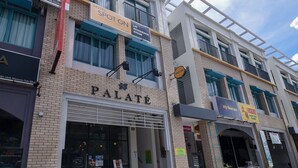 Un edificio de varios pisos que alberga diversos comercios, incluyendo una boutique, un hotel excelente y un restaurante de exquisitez.