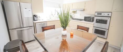 A modern kitchen with stainless steel appliances, a central island, and a potted plant.