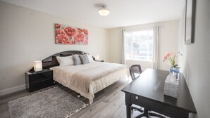 Ein Schlafzimmer mit einem Bett, Nachttischen, einem Schreibtisch und einem Fenster.