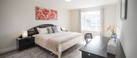 A bedroom with a bed, bedside tables, a desk, and a window.