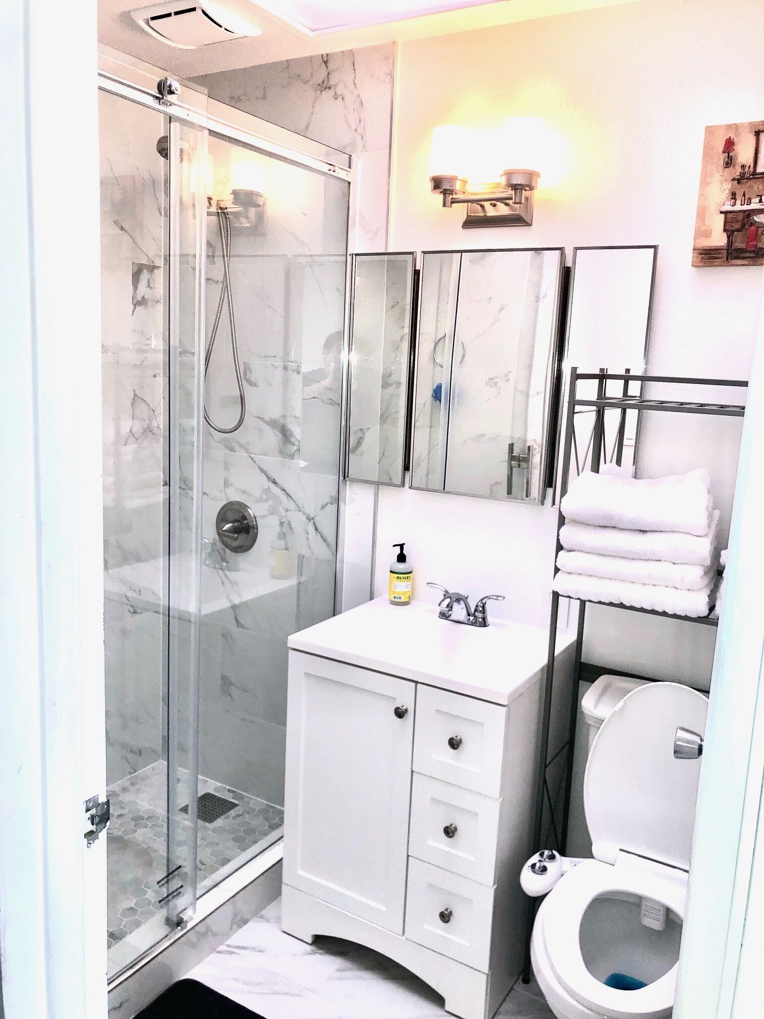 A bathroom with a glass-enclosed shower, a white vanity with a mirror, and a toilet.