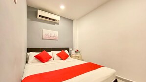 A neatly made bed with white and red bedding, a small bedside table with a vase of flowers, and a wall-mounted air conditioner. - SPOT ON 90283 27 Muntri (George Town)