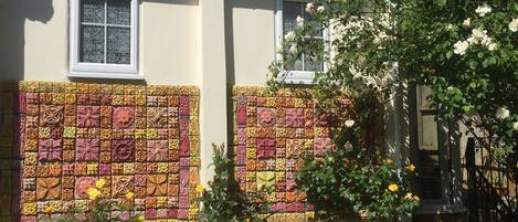 A building with a colorful mosaic wall and a garden with roses.