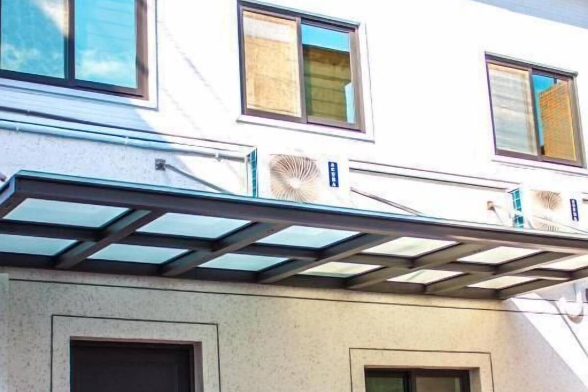 A building with a covered patio area, a door, and a bench.