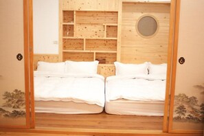 Una habitación con dos camas, paneles de madera, un tragaluz circular y un pequeño armario.