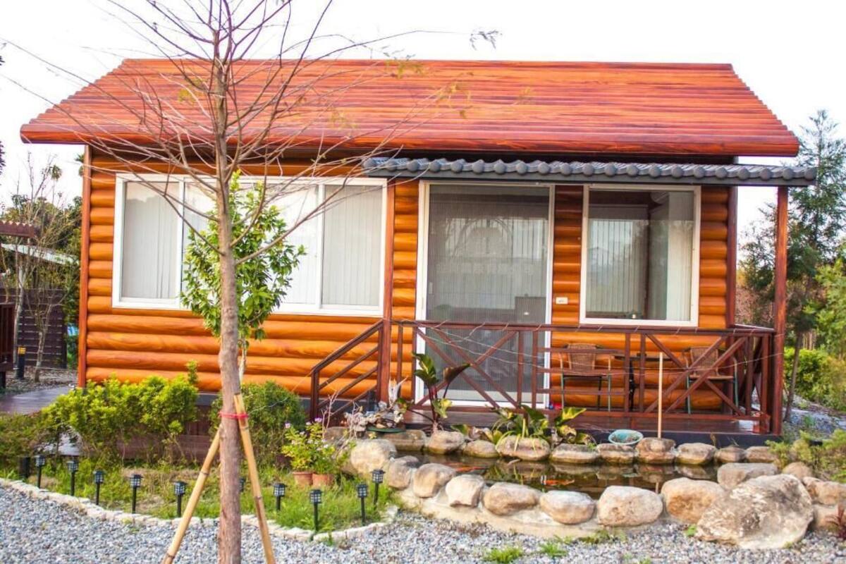 A log cabin with a porch, large windows, and a stone pathway.