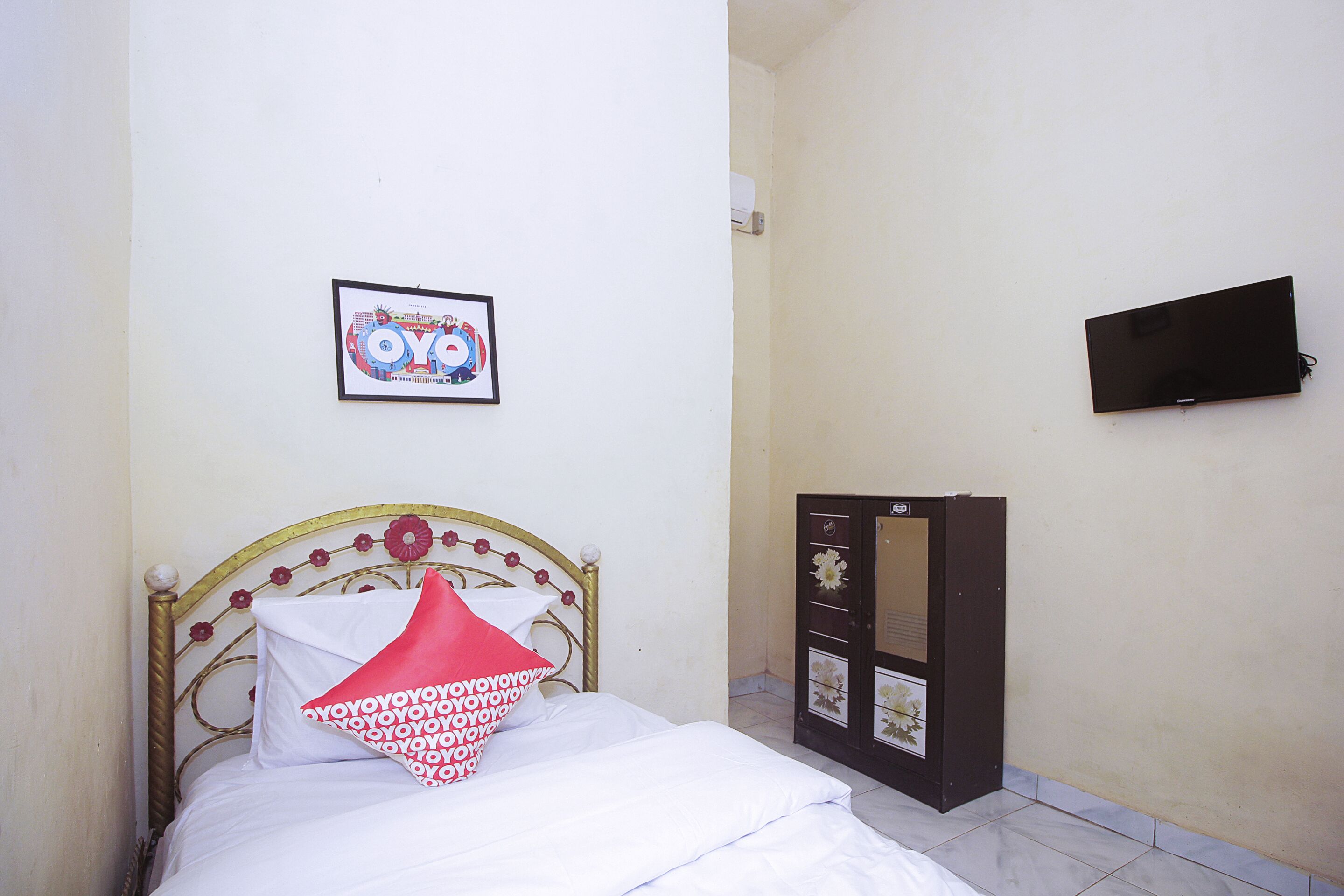 A room with a bed, a framed picture on the wall, and a TV mounted on the wall.