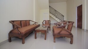 A living room with a sofa, armchairs, and a coffee table. A staircase with a railing is visible in the background. - Hotel O Diva Residen Syariah (Jambi)