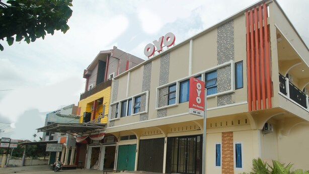 A multi-story building with a prominent 'OYO' sign, indicating it is a hotel. There are multiple balconies and large windows. - Hotel O Diva Residen Syariah (Jambi)