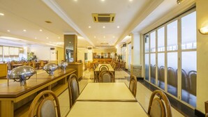 A spacious hotel dining area with long tables and chairs, a buffet station, and large windows offering views. - Super OYO Collection O 25 Hotel Baltika (Bandung)