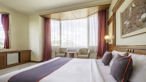 A hotel room with a large bed, two armchairs, a small table, and a painting on the wall. - Super OYO Collection O 25 Hotel Baltika (Bandung)