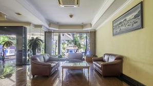 A lobby with two leather sofas, a glass coffee table, and a large framed picture on the wall. - Super OYO Collection O 25 Hotel Baltika (Bandung)