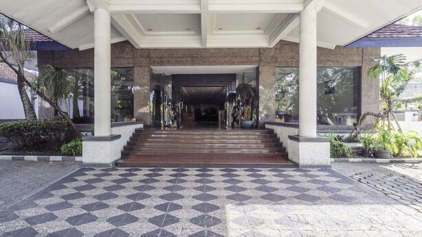 A building entrance with a checkered floor, steps leading up to a covered area, and columns. - Super OYO Collection O 25 Hotel Baltika (Bandung)