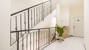 A staircase with a black metal railing, a potted plant, and a door with a sign.