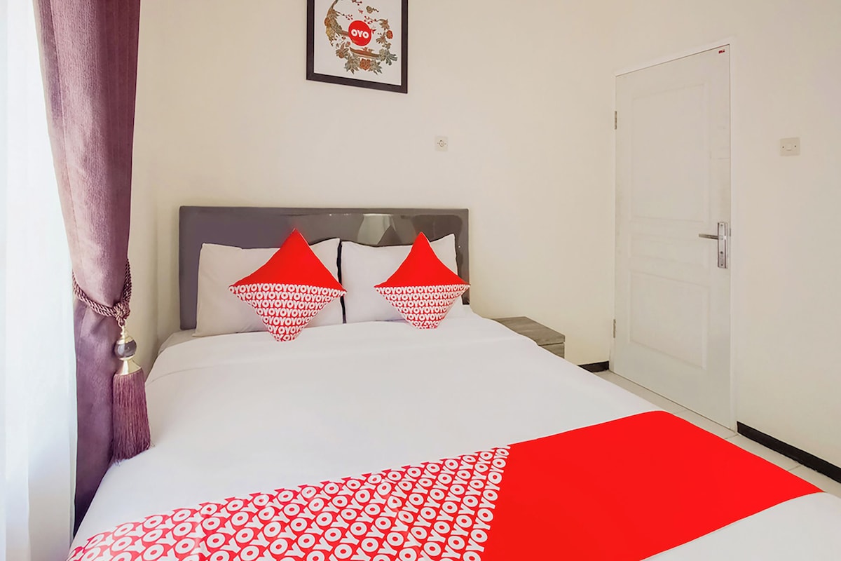 A hotel room with a bed, a door, and a wall-mounted picture.