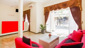 A hotel lobby with red furniture, a white coffee table, and a potted plant.