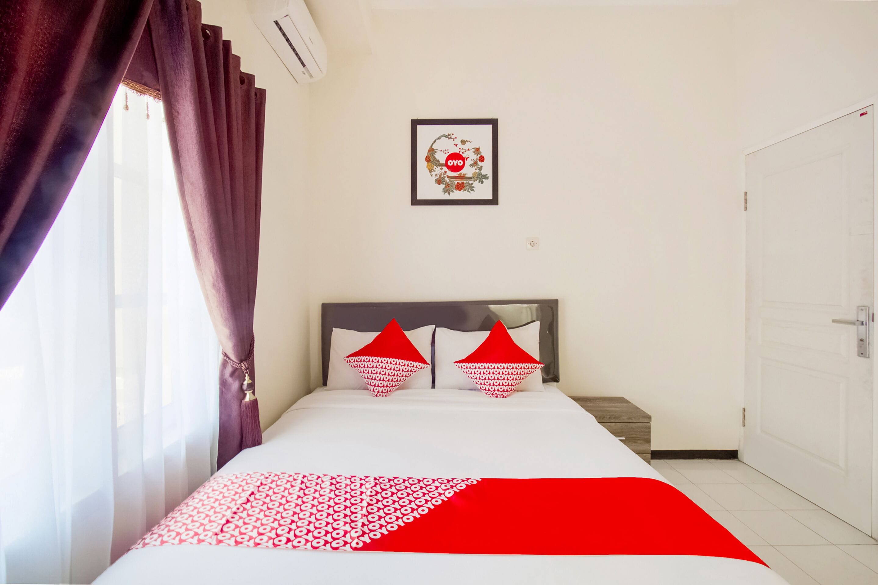 A bedroom with a bed, a headboard, a wall-mounted picture, and a door.