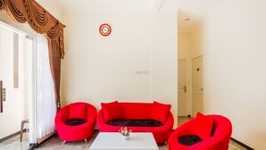 A living room with a red sofa set, a white coffee table, and a red armchair.