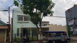 A building with a gated entrance, a parked scooter, and a food truck. - OYO 2753 Irma's Residence (Blitar)