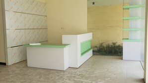 A reception desk with a green top, a white counter, and a green shelf. - OYO 2753 Irma's Residence (Blitar)