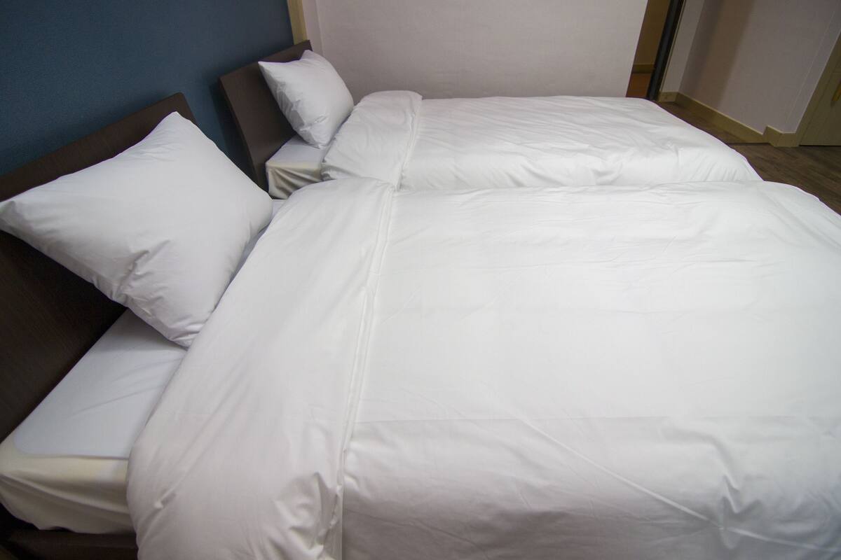 Een opgemaakt bed met witte lakens in een hotelkamer.