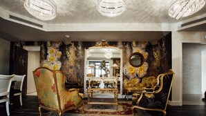 Een luxe kamer met versierde meubels, een grote spiegel en decoratieve wandpanelen.