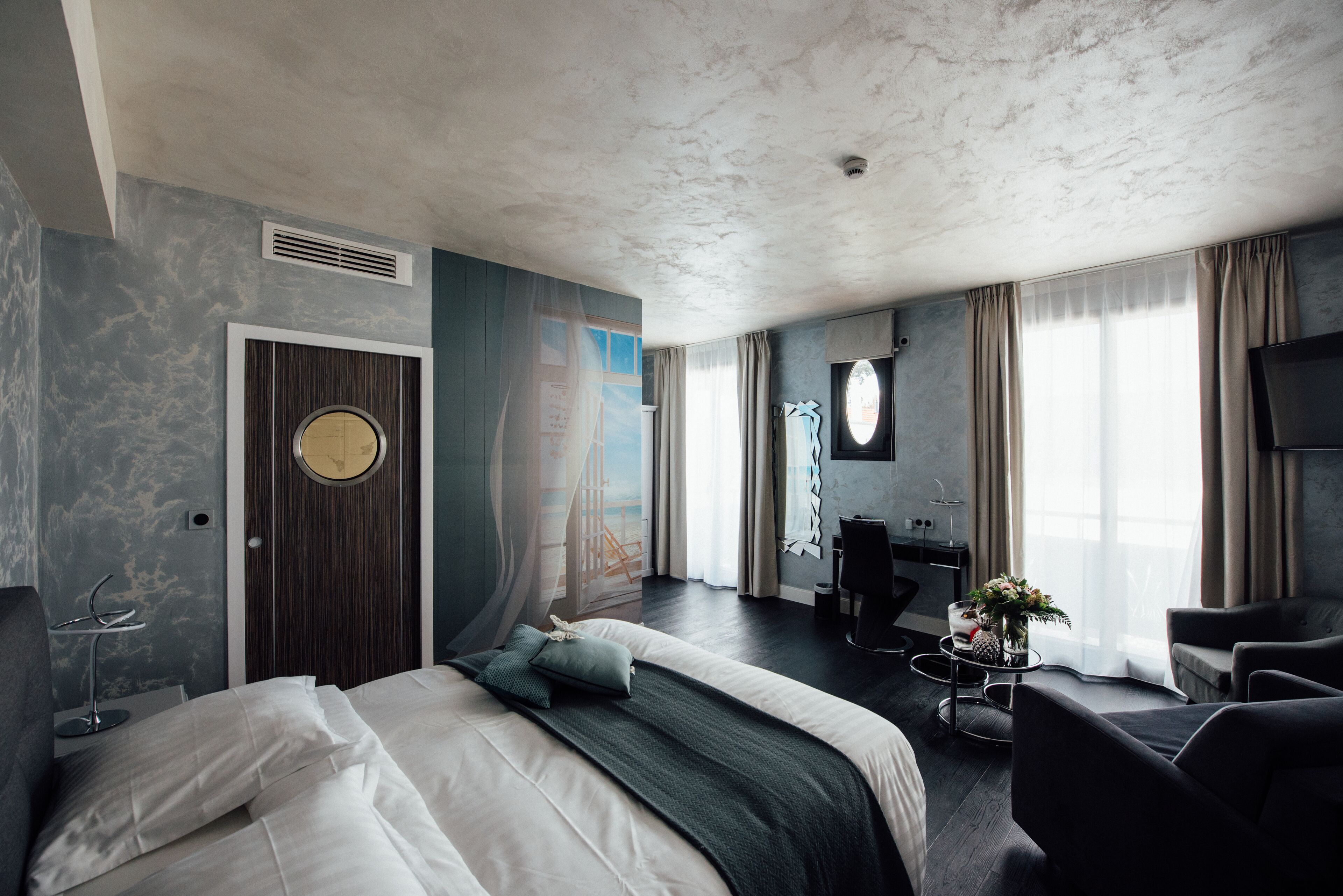 A modern hotel room with a large bed, a desk, and a seating area.